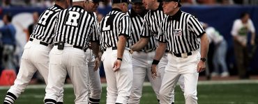 [IMAGE] A group of American Football referees in striped jerseys are having a conversation