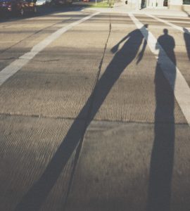 [IMAGE] White lines painted on a road. Three shadows of people originating from near the camera are cast across the road and one of the lines